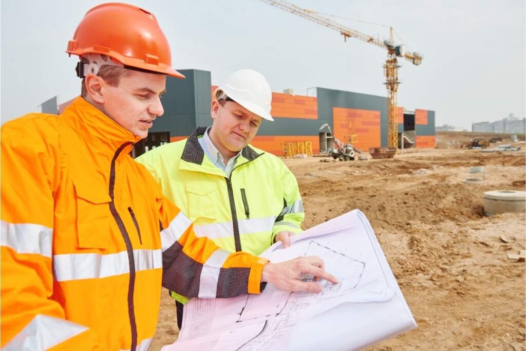 A contractor conducting site planning while holding a building layout plan